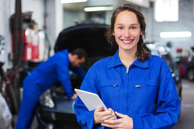 woman auto mechanic smiling holding a clipboard
