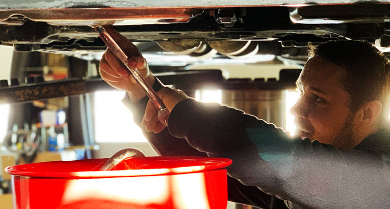 auto mechanic working on the bottom of a car